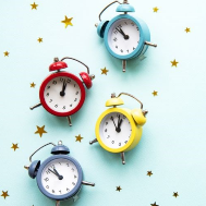 Alarm clocks and star confetti on light teal background