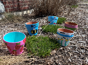A photo of clay pots that have been painted by children.