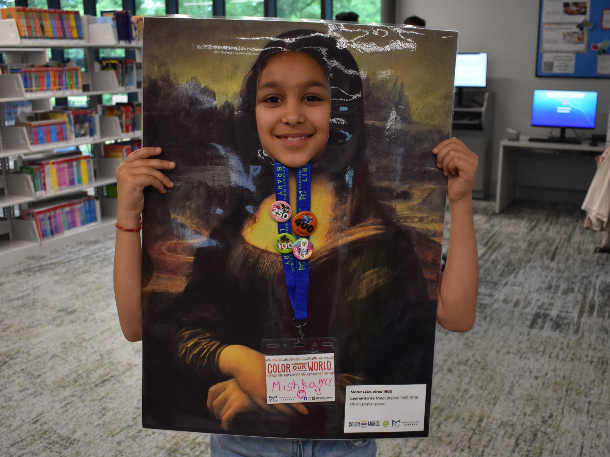 A little girl is posing with a Mona Lisa photo prop in which the face of the painting is cut out and the little girl's face is sticking out of the painting as if she is the famous Mona Lisa. The little girl is smiling and wearing her FCPL summer reading lanyard complete with several buttons earned during the summer reading challenge. A little girl is posing with a Mona Lisa photo prop in which the face of the painting is cut out and the little girl's face is sticking out of the painting as if she is the famous Mona Lisa. The little girl is smiling and wearing her FCPL summer reading lanyard complete with several buttons earned during the summer reading challenge.