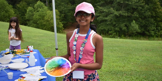 A tween-age girl sporting a very full summer reading lanyard is displaying some color-theory art she made at a recent Bookmobile event. She looks like the kind of library user who would really enjoy the exclusive "WOW!" button now available during the month of July only, while supplies last!