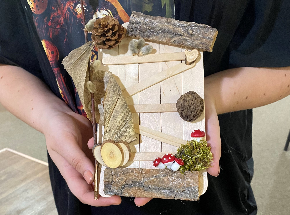 A child holds out a "fairy door" craft,