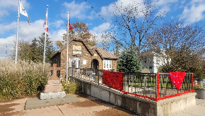 A photo of the exterior of the Newbury Library. The railing along the access ramp is decorated with crocheted poppies.