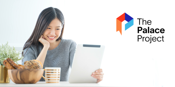 Woman sitting at a table, drinking from a mug, and reading an electronic tablet.