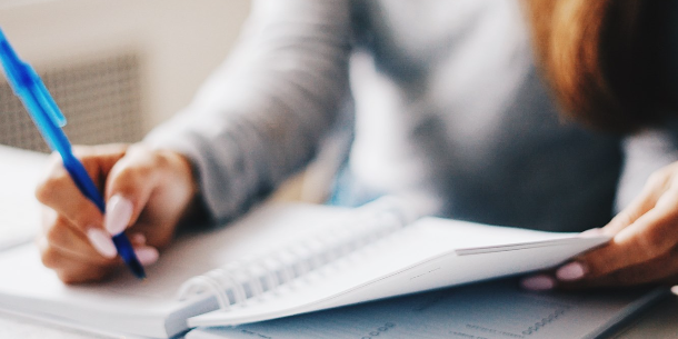 Closeup of a woman's hand writing in her calendar. 