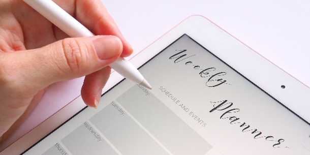 Close up of a hand using a digital tablet to plan a weekly schedule in a digital calendar