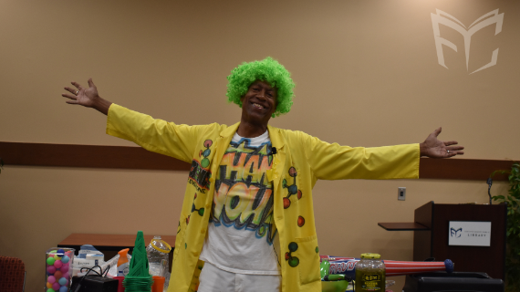 Michael Green the Science Machine smiling and holding his hands out at a library event. 