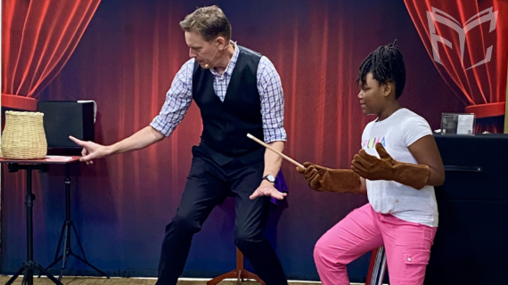 Magician Brian Robert doing a magic trick with a young patron. 