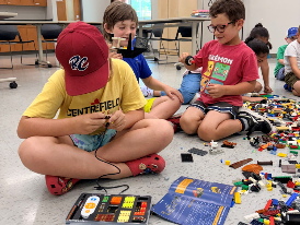 Three children playing with Sparkblocks and Lego at the Komoka Library.