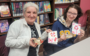 Two program participants show the camera the card and candle they made.