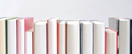 Stack of books next to laptop 