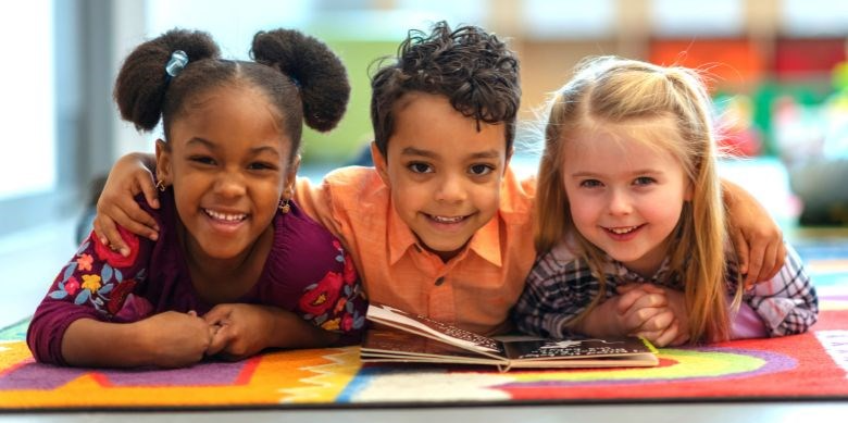 Three kids reading a book in a library