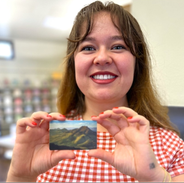 Woman in red checked shirt holding up a library card