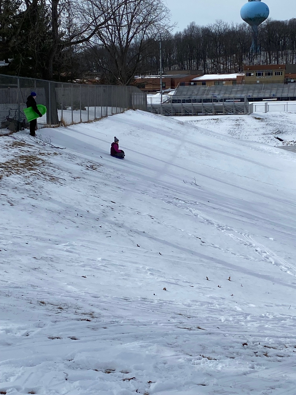 Image of two teens sledding down a hill. 