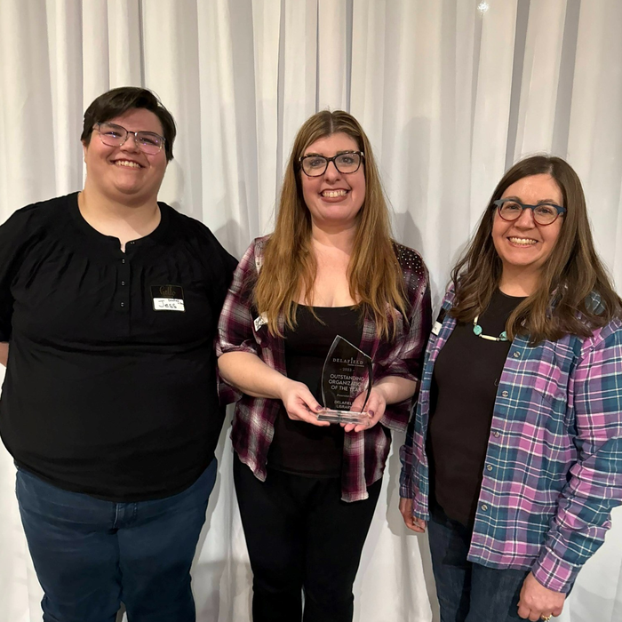 Photo of Delafield Public Library Director and two staff smiling at the camera and holding "Outstanding Organization of the Year" award. 