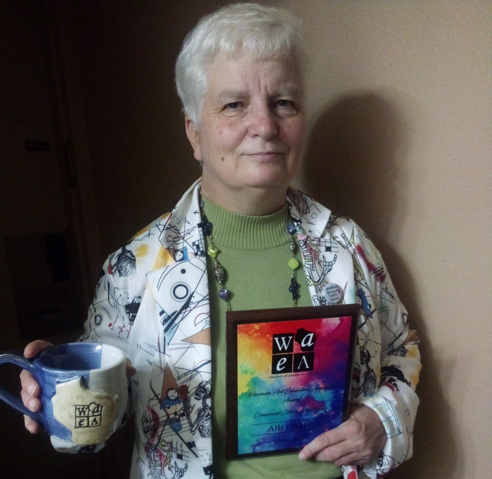 Photo of Alli Chase holding her Concerned Citizen of the Year Award and a WAEA mug.