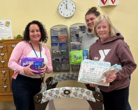 Photo of Library Director, Administrative Coordinator, and the President of the Friends of the Library all holding diaper packages.