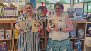 Librarians holding the Evening, Morning, and UFO Festival Book Group books in front of the new book shelf on the main floor of the library. Librarians holding the Evening, Morning, and UFO Festival Book Group books in front of the new book shelf on the main floor of the library.