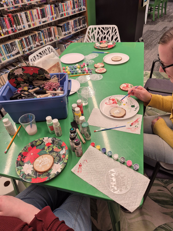 Librarian Shelby and a teen decorating wooden ornaments in the Teen Scene.