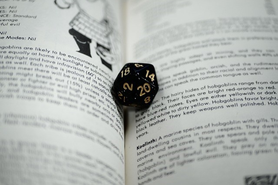 An open D&D book and a polyhedral die.